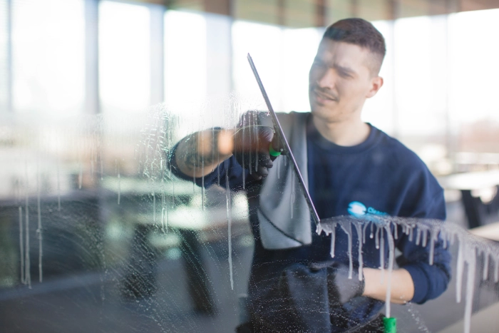 CleanFix Service Glasreinigung Abziehen Fenster Nahaufnahme Reiniger zieht nasses Glas mit Glasabzieher ab — Blick durch die Scheibe — CleanFix Service