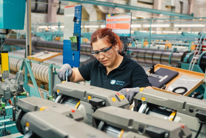 CleanFix Service Industriereinigung Maschinenreinigung Detail Reinigungskraft mit Schutzbrille reinigt Maschinenteile in einer Produktionshalle — CleanFix Service