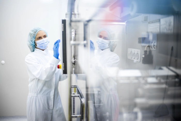 CleanFix Service Reinraumreinigung Schutzanzug Sterilbereich Reinigungskraft in Schutzanzug, Haube und Maske reinigt Gerät im Reinraum — CleanFix Service