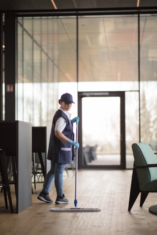 CleanFix Service Unterhaltsreinigung Empfangsbereich Mopp Reinigungskraft wischt Holzboden im Empfangsbereich eines modernen Gebäudes mit Mopp — CleanFix Service - Gebäudereinigung Reutlingen