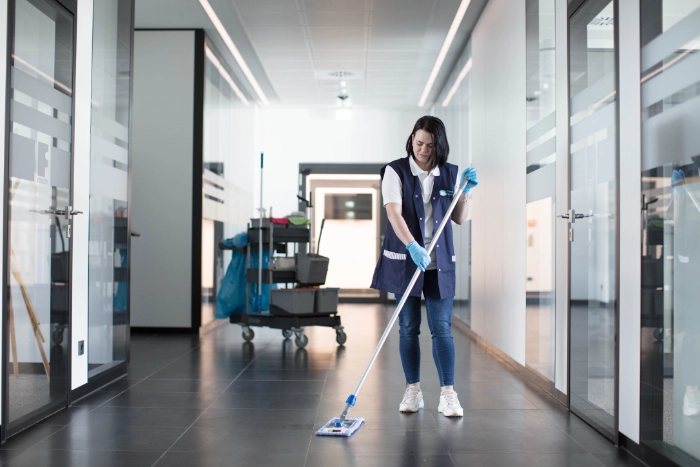 CleanFix Service Unterhaltsreinigung Bürogebäude Flur Mopp Reinigungskraft wischt Flurboden im Bürogebäude mit Mopp — CleanFix Service
